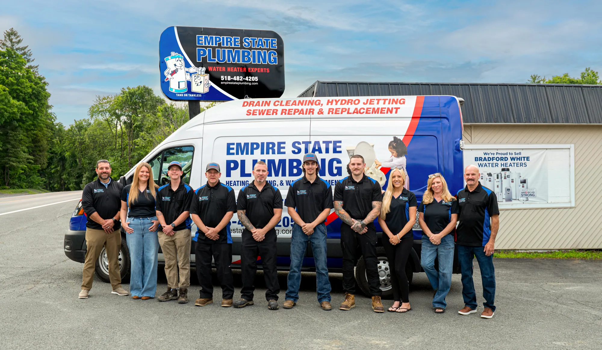 The full Empire State Plumbing team standing together in front of a company service van at their Nassau, NY shop