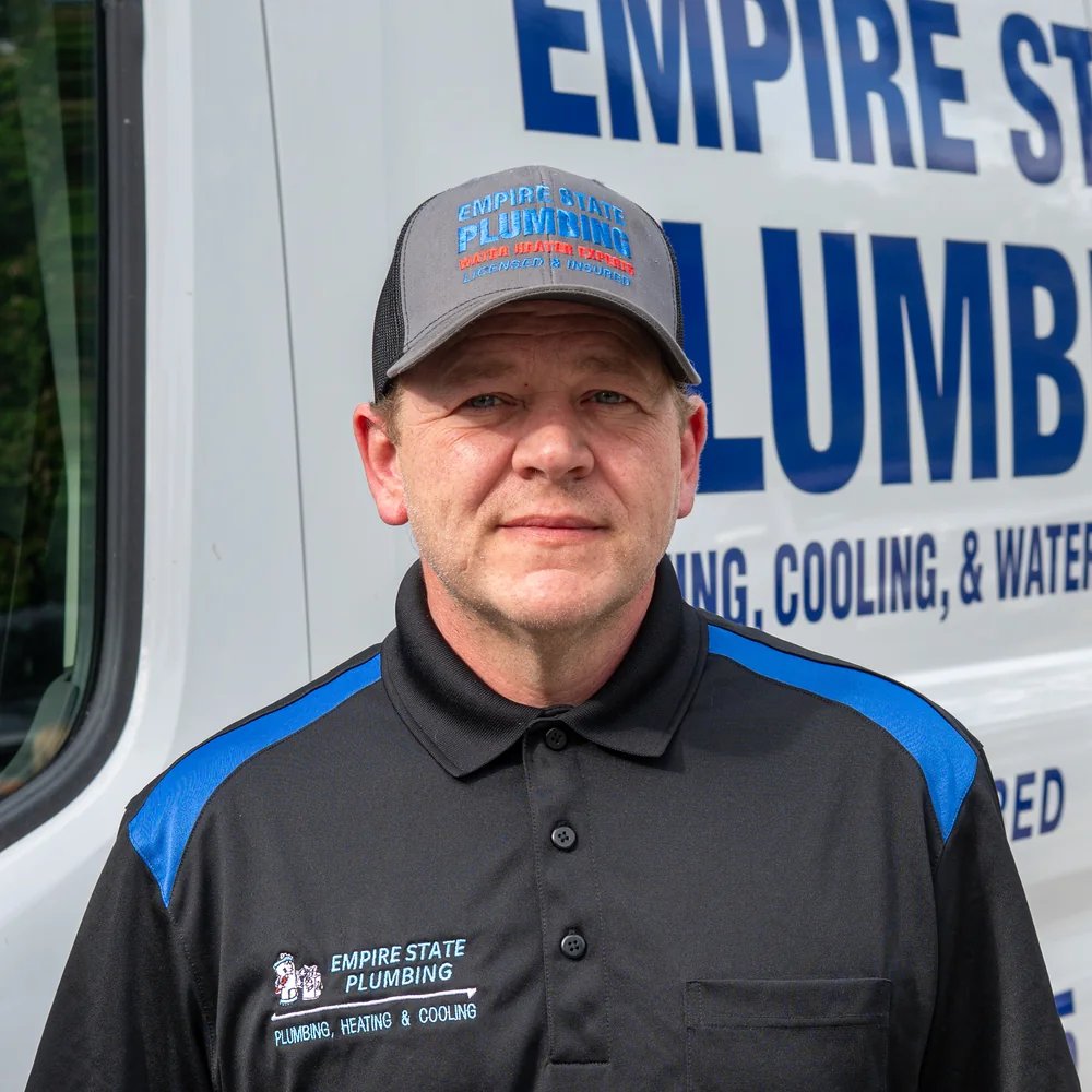 Empire State Plumbing service technician in front of a branded company van