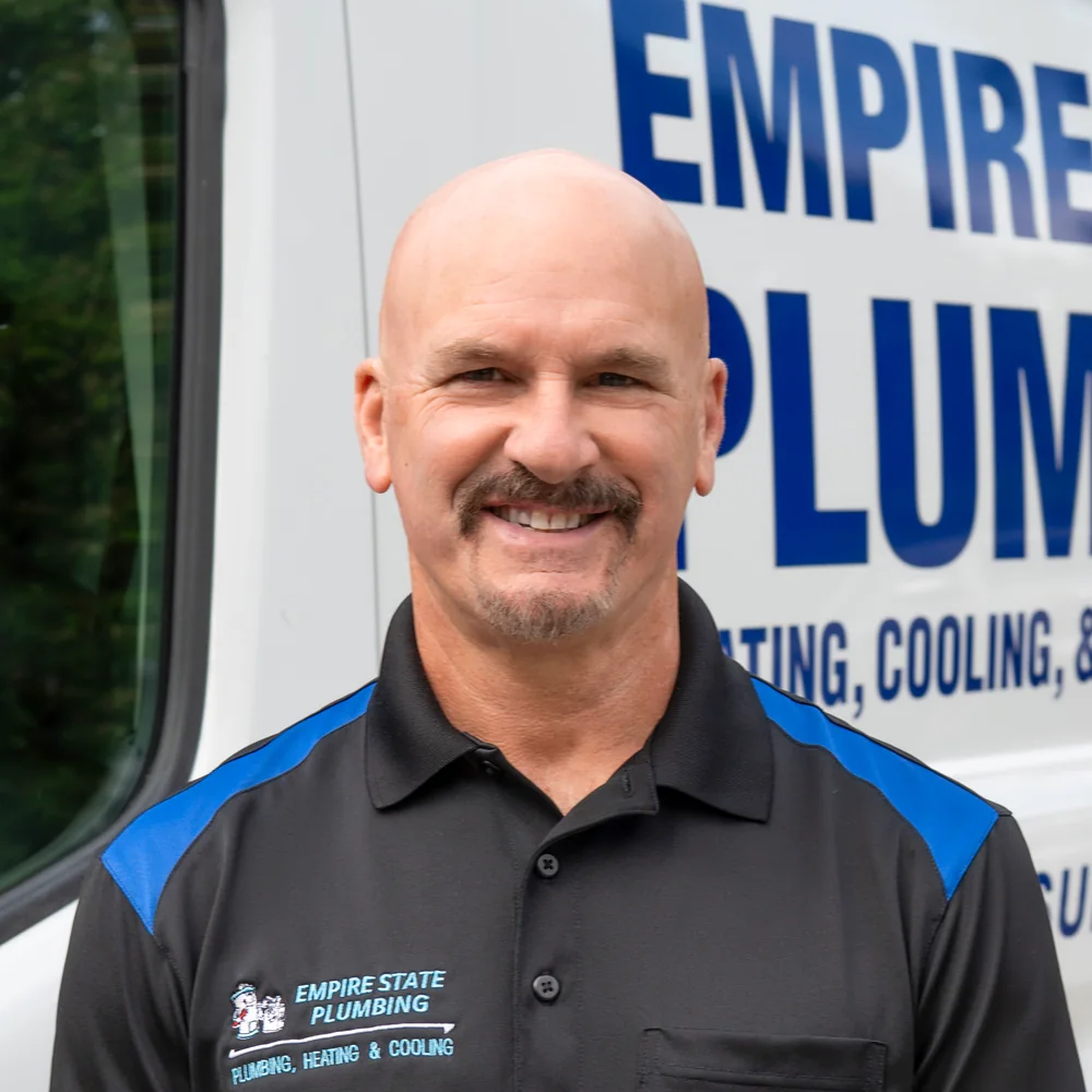 Empire State Plumbing service technician standing beside a company van