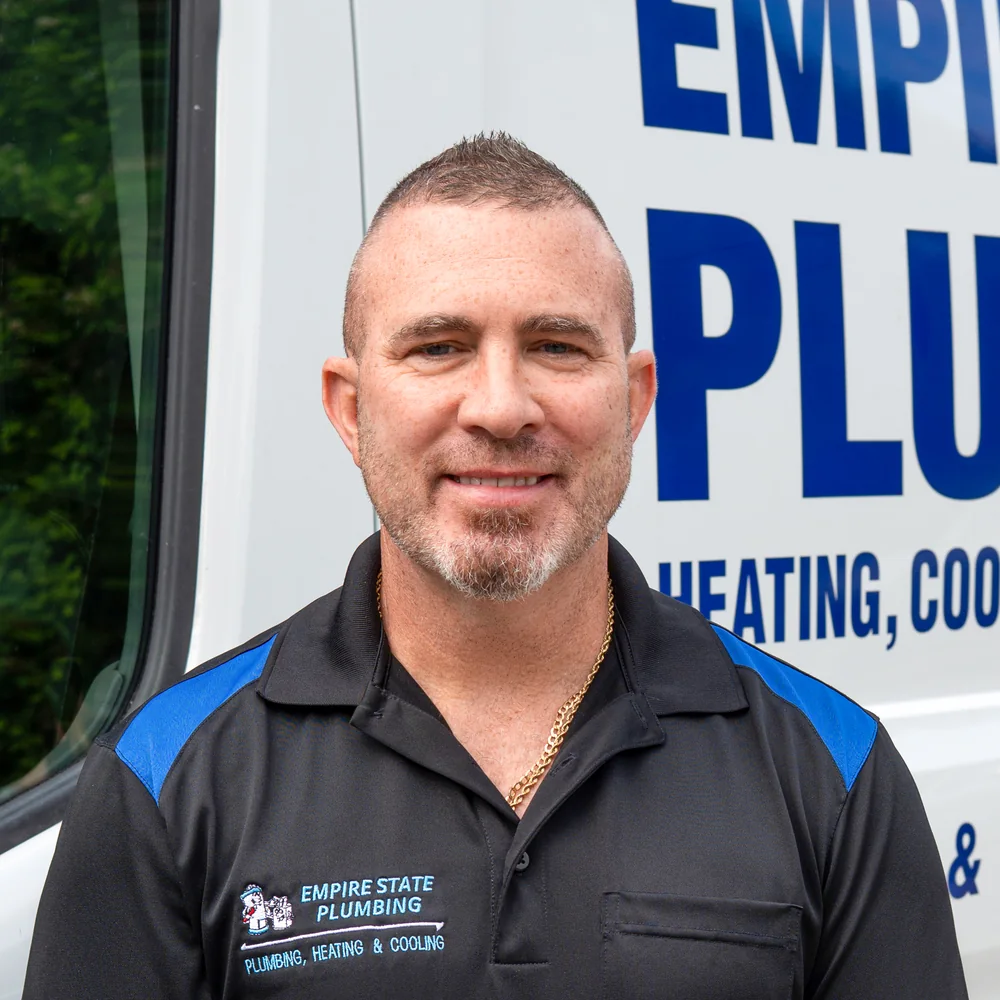 Empire State Plumbing technician in front of an Empire State Plumbing van