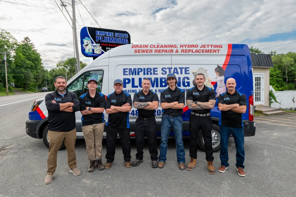 Empire State Plumbing licensed technicians lined up in front of a branded service van at the Nassau NY shop