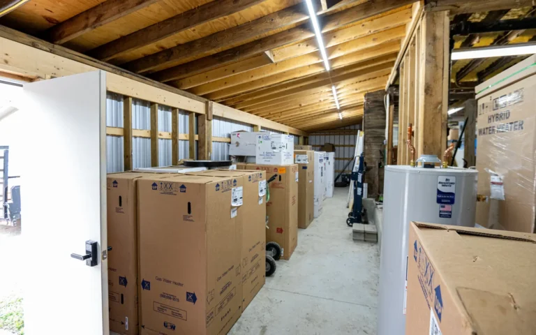 Rows of new gas and hybrid water heaters staged in the Empire State Plumbing warehouse, ready for same-day install
