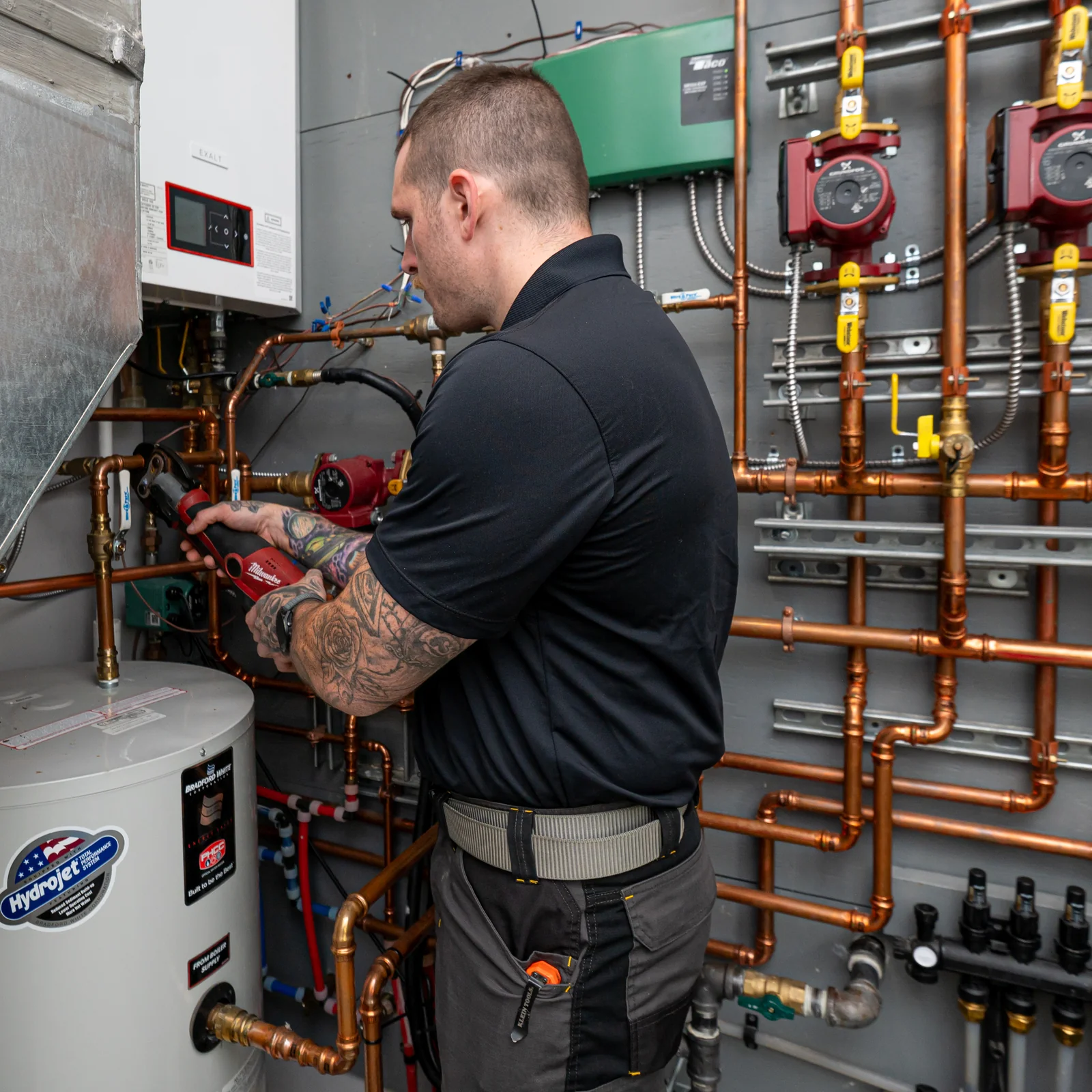 Empire State Plumbing technician connecting copper piping on a Bradford White water heater and boiler system in a Capital Region mechanical room